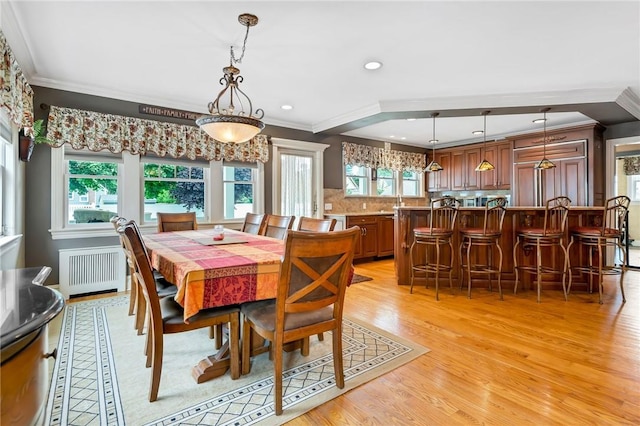 dining space featuring radiator heating unit, light wood-type flooring, plenty of natural light, and ornamental molding