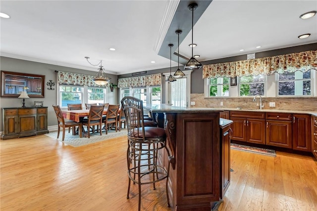 kitchen featuring hanging light fixtures, light hardwood / wood-style flooring, plenty of natural light, and a breakfast bar area