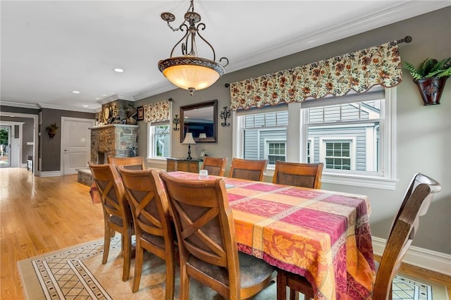 dining space with crown molding, a fireplace, and light hardwood / wood-style floors