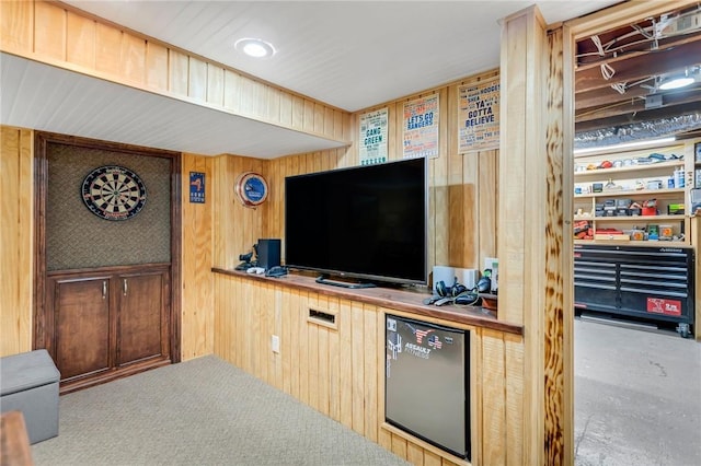 interior space with stainless steel refrigerator, wooden walls, and light carpet