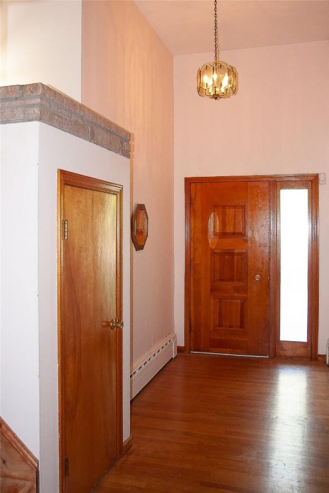 foyer featuring wood-type flooring, a notable chandelier, and a baseboard heating unit