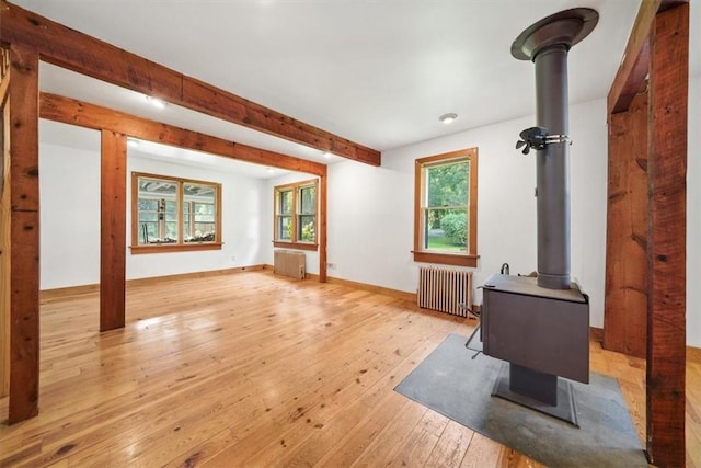 living room featuring radiator heating unit, light hardwood / wood-style floors, and a wood stove