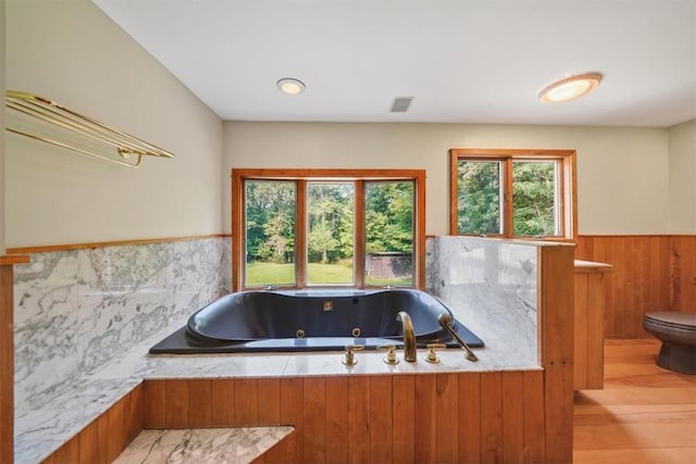 bathroom with a tub, hardwood / wood-style floors, and toilet