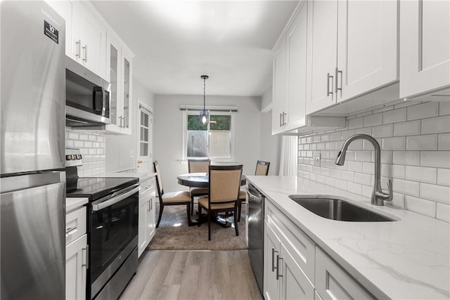 kitchen featuring stainless steel appliances, white cabinetry, light hardwood / wood-style floors, and sink