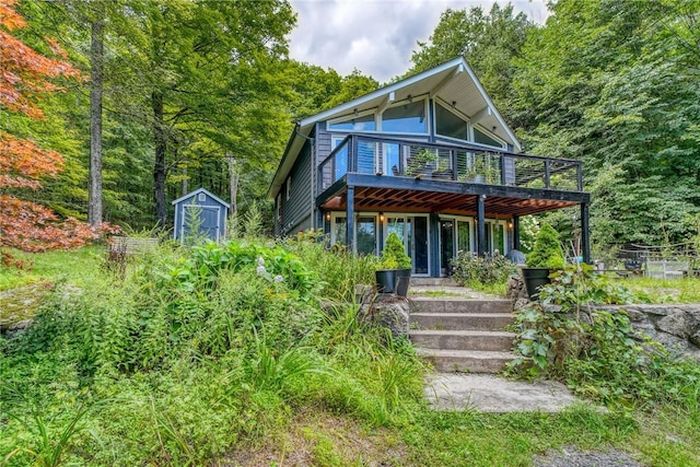 back of property with a storage shed and a wooden deck