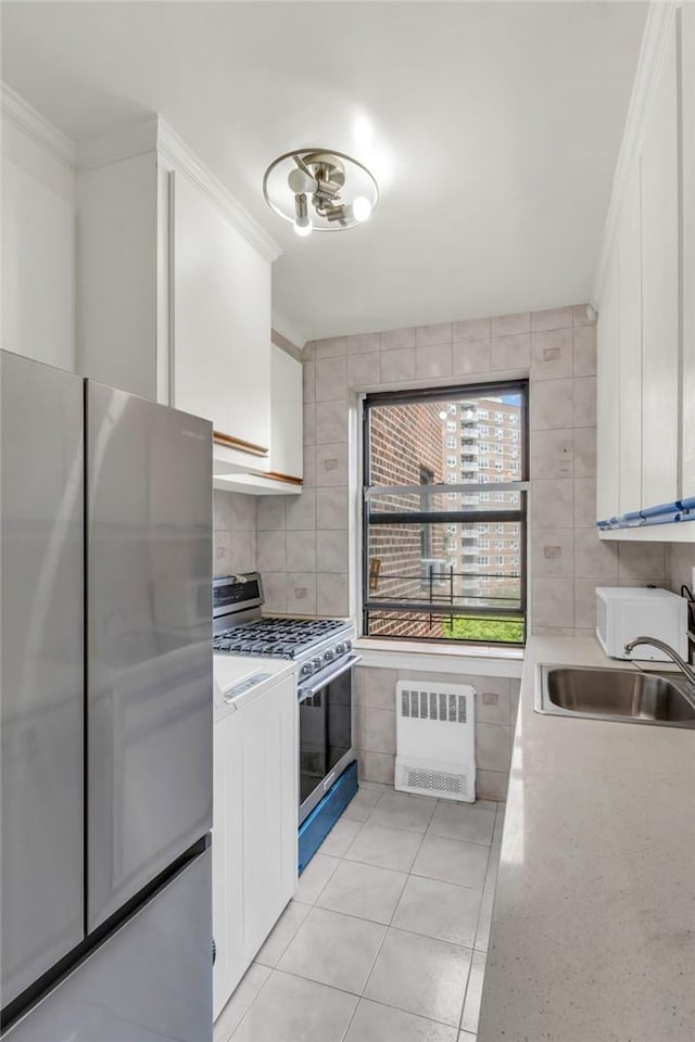 kitchen featuring radiator heating unit, sink, white cabinetry, and stainless steel appliances