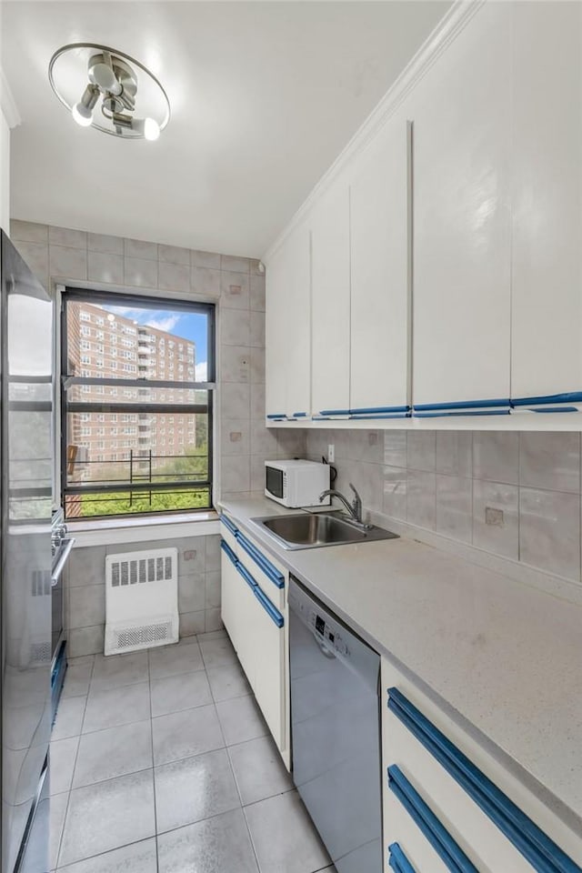 kitchen with sink, light tile patterned floors, white cabinetry, radiator heating unit, and stainless steel appliances