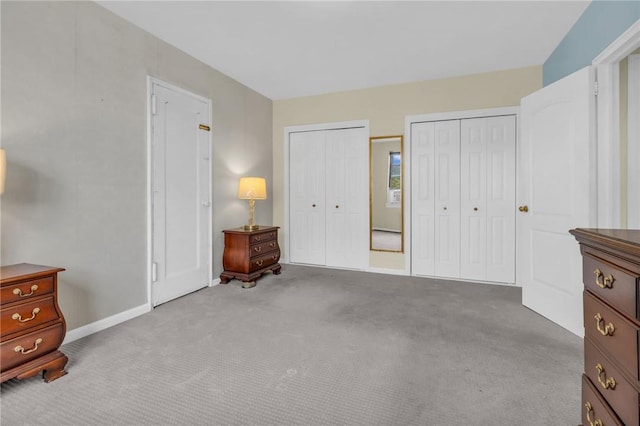 bedroom featuring light colored carpet and two closets