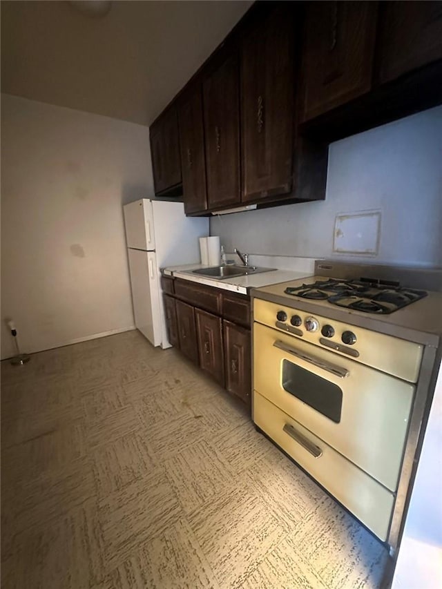 kitchen featuring dark brown cabinetry, sink, range with gas cooktop, and white refrigerator