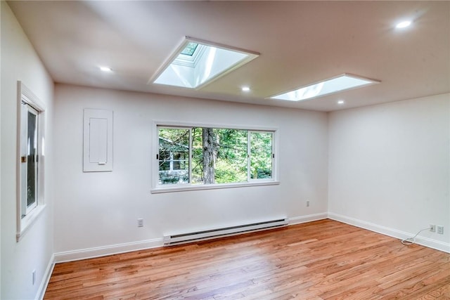 empty room with a skylight, light hardwood / wood-style floors, and a baseboard heating unit