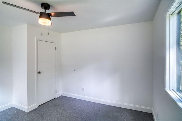 spare room with ceiling fan and dark carpet