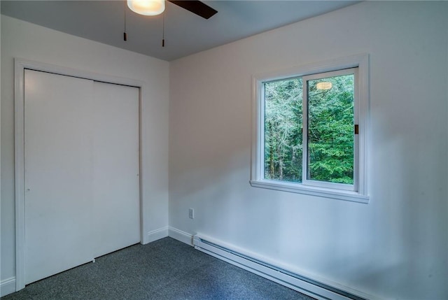 unfurnished bedroom with dark colored carpet, a closet, ceiling fan, and a baseboard heating unit