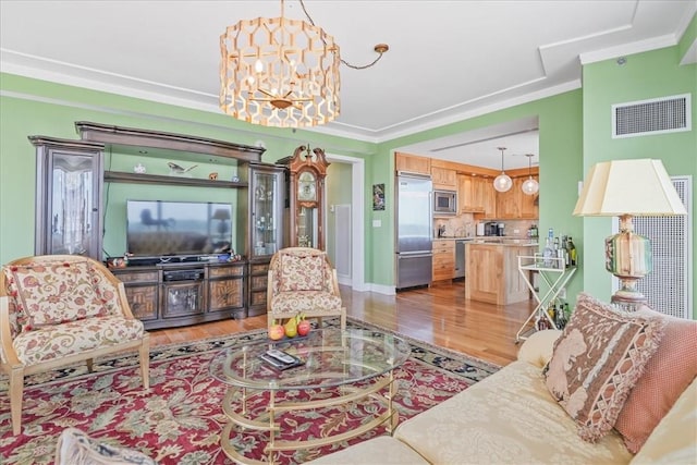 living room with an inviting chandelier, light hardwood / wood-style flooring, and crown molding