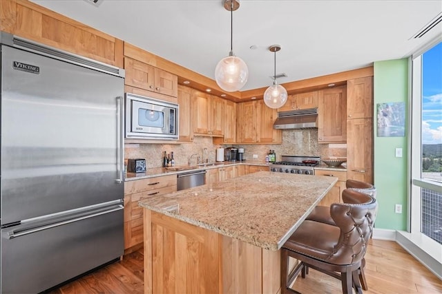 kitchen with built in appliances, a center island, plenty of natural light, and light wood-type flooring