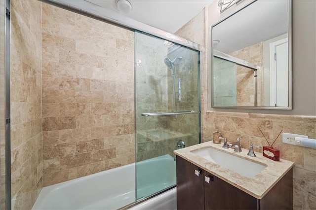 bathroom with vanity, enclosed tub / shower combo, and tile walls