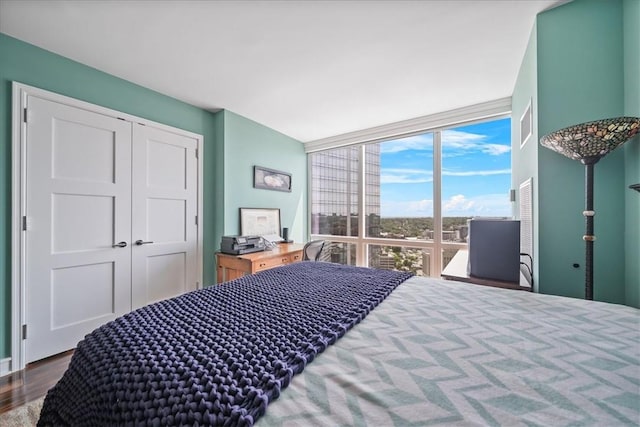 bedroom featuring floor to ceiling windows, a closet, and hardwood / wood-style flooring