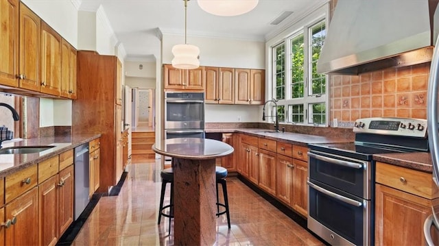 kitchen with crown molding, sink, wall chimney exhaust hood, appliances with stainless steel finishes, and a kitchen bar