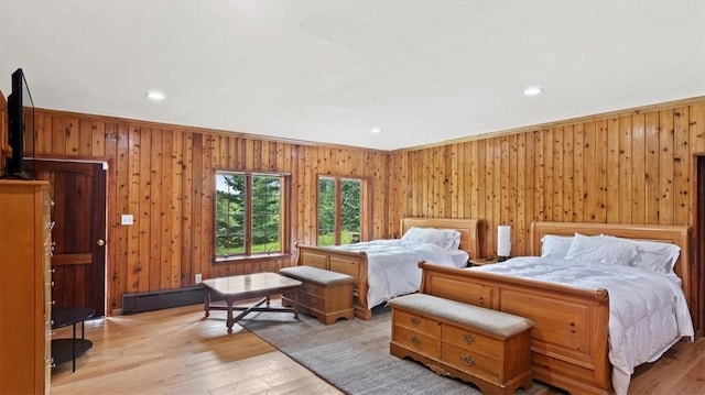 bedroom featuring wooden walls, light hardwood / wood-style flooring, a baseboard heating unit, and ornamental molding