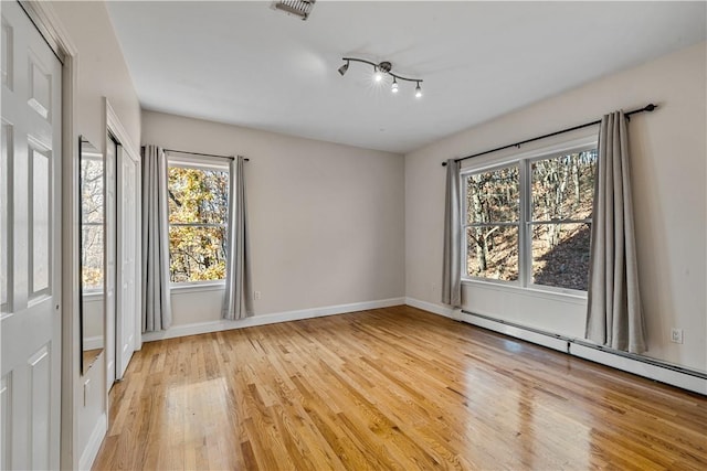 empty room featuring a baseboard radiator and light hardwood / wood-style flooring