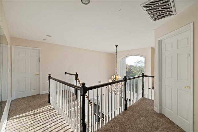 hallway with carpet and a notable chandelier