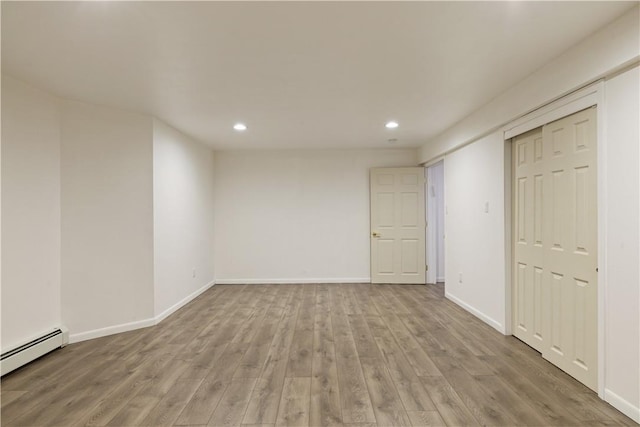 unfurnished room featuring light hardwood / wood-style floors and a baseboard radiator