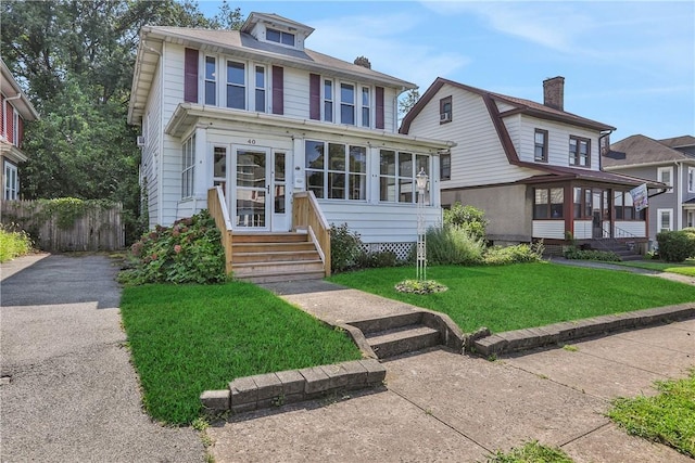 view of front of home with a front yard and a sunroom