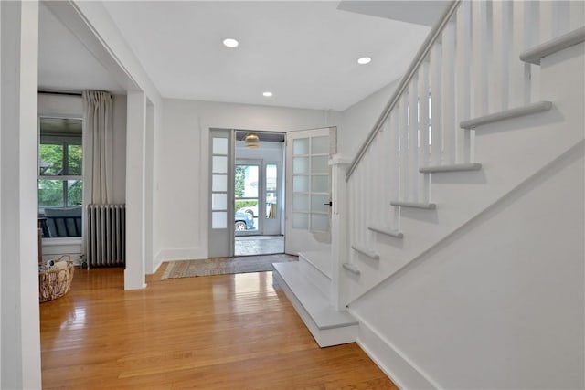 entrance foyer featuring hardwood / wood-style flooring, plenty of natural light, radiator, and french doors