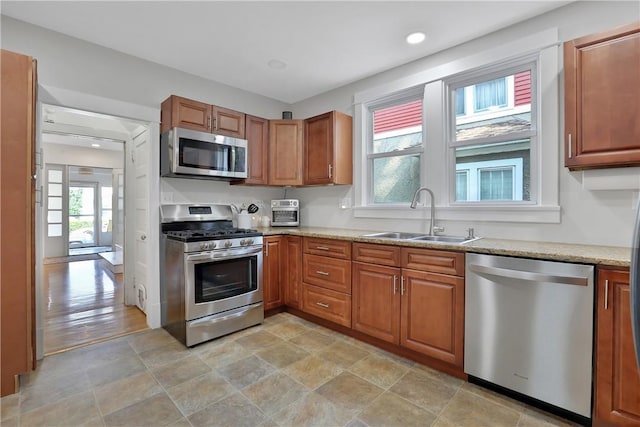 kitchen with appliances with stainless steel finishes, light stone counters, and sink