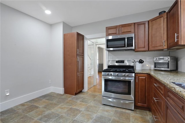 kitchen featuring light stone counters, radiator, and appliances with stainless steel finishes