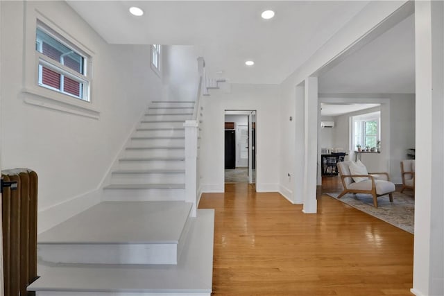 stairway with an AC wall unit and hardwood / wood-style floors