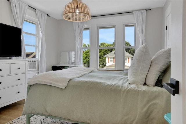 bedroom featuring hardwood / wood-style floors, multiple windows, and cooling unit