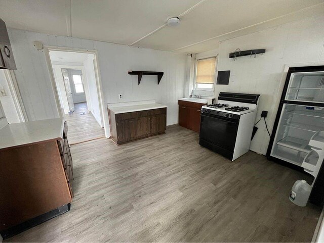 kitchen featuring a healthy amount of sunlight, light wood-type flooring, white range with gas cooktop, and fridge