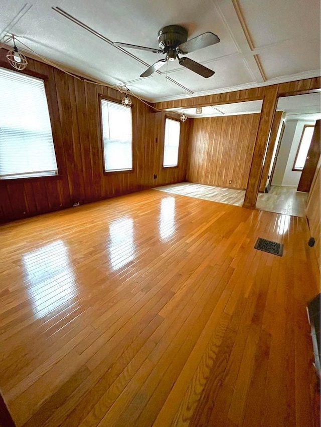 spare room with wooden walls, ceiling fan, and light wood-type flooring