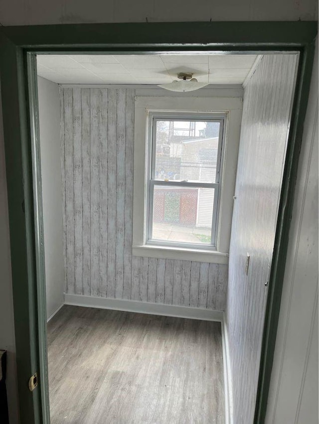 unfurnished room featuring wood-type flooring and wooden walls