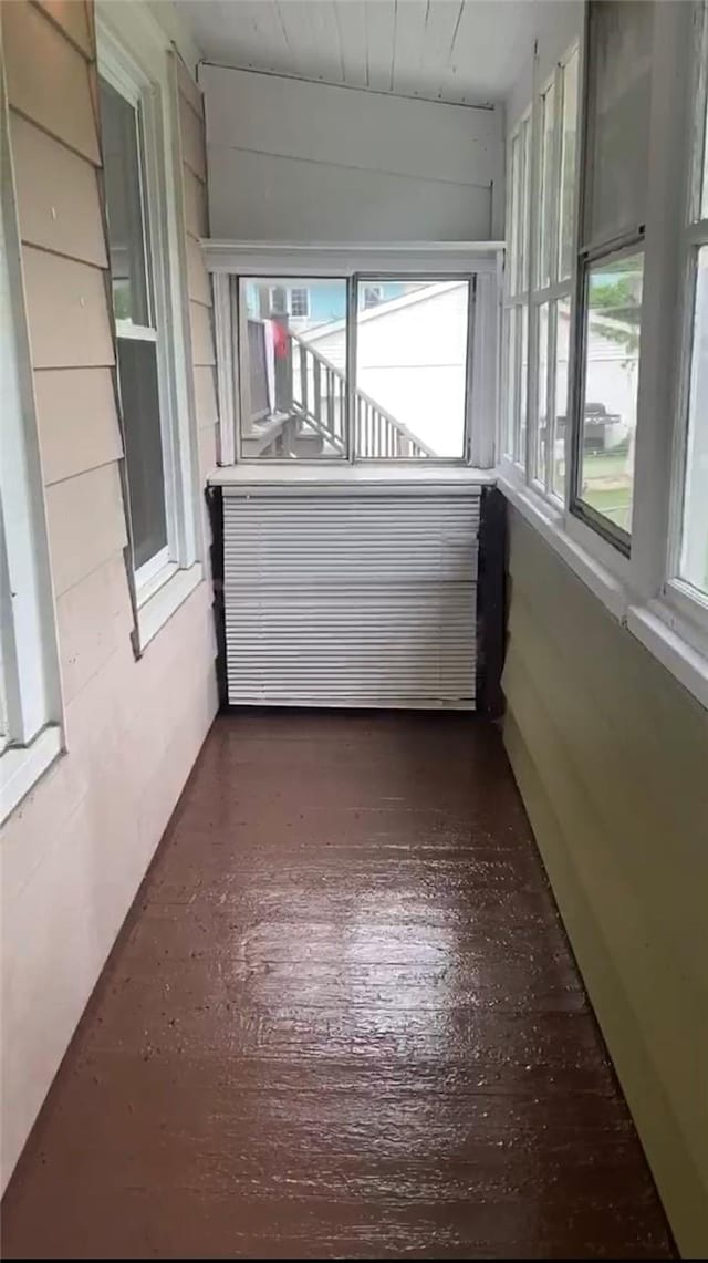 unfurnished sunroom featuring radiator heating unit and lofted ceiling