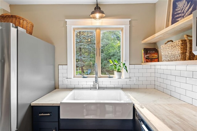 kitchen featuring pendant lighting, stainless steel refrigerator, plenty of natural light, and sink