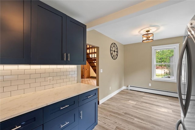 kitchen featuring decorative backsplash, light wood-type flooring, blue cabinetry, and light stone countertops