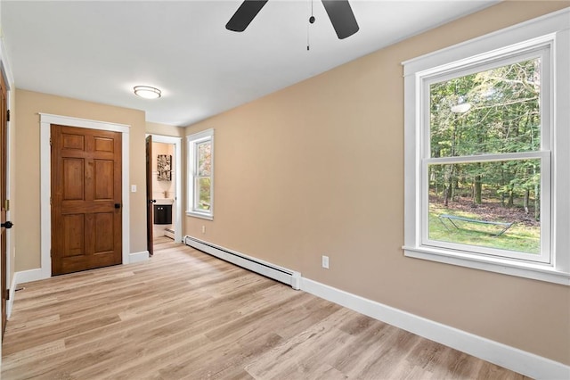 interior space with a wealth of natural light, a baseboard radiator, and light hardwood / wood-style floors