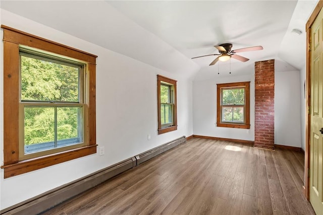 empty room featuring hardwood / wood-style flooring, plenty of natural light, vaulted ceiling, and a baseboard radiator