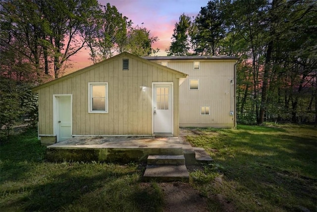 back house at dusk featuring a yard