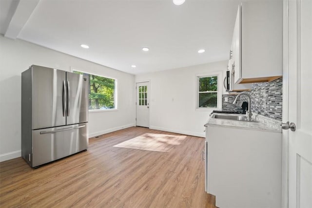 kitchen featuring stainless steel fridge, white cabinetry, a wealth of natural light, and sink