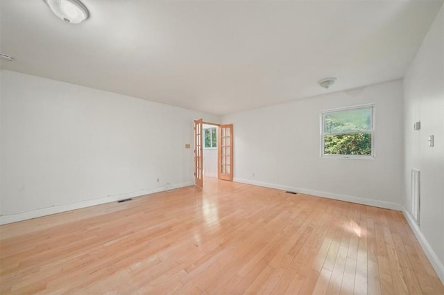 empty room with a wealth of natural light and light hardwood / wood-style flooring