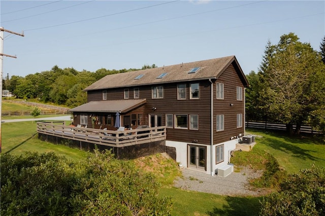 back of property with a deck, a yard, and central air condition unit