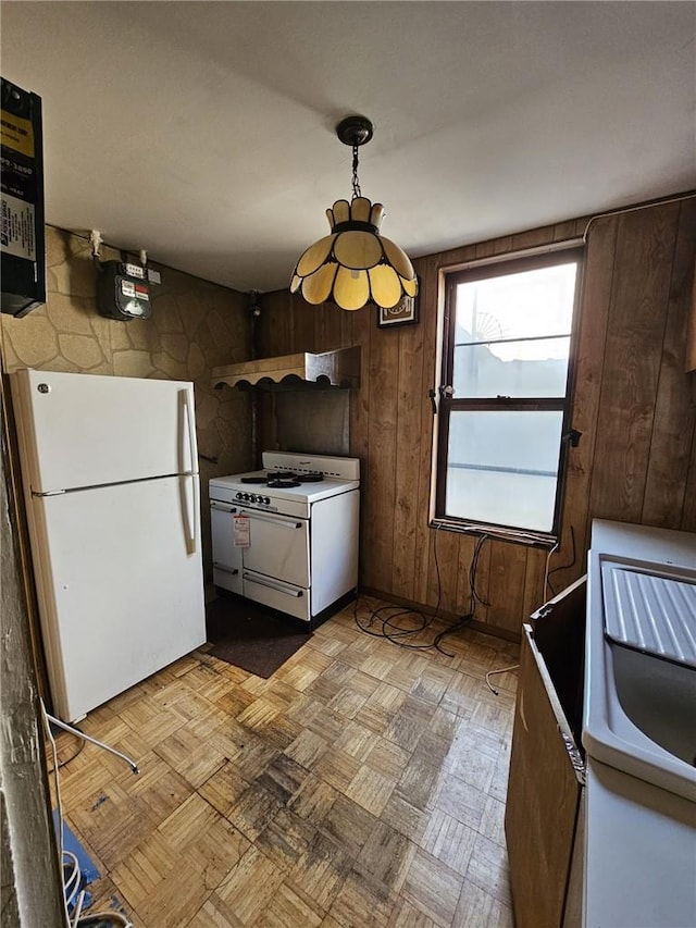 kitchen with dark brown cabinetry, white appliances, wooden walls, and light parquet flooring