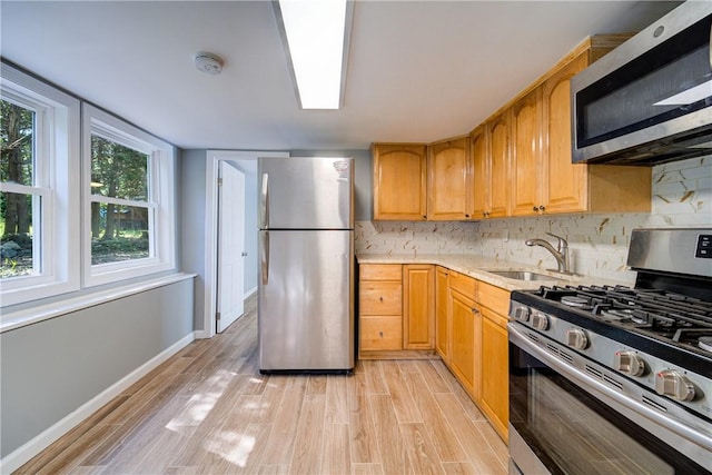 kitchen featuring light wood-type flooring, stainless steel appliances, tasteful backsplash, and sink