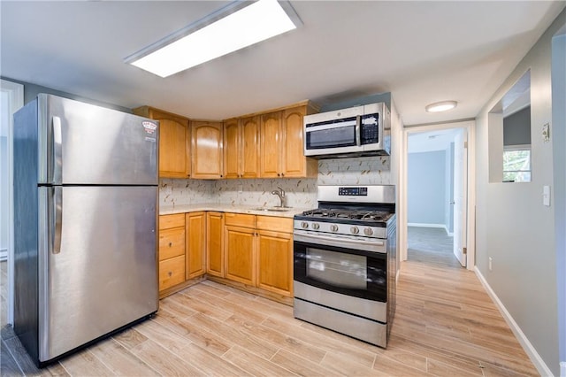 kitchen featuring decorative backsplash, stainless steel appliances, light hardwood / wood-style floors, and sink