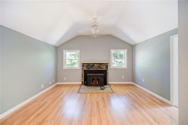 unfurnished living room featuring a fireplace, vaulted ceiling, light hardwood / wood-style flooring, and a wealth of natural light