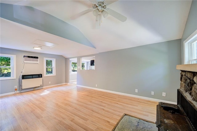 unfurnished living room featuring a wall mounted air conditioner, heating unit, light hardwood / wood-style floors, a stone fireplace, and lofted ceiling