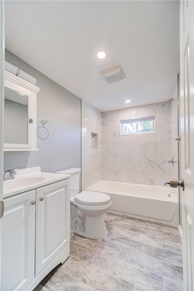 full bathroom with vanity, tiled shower / bath combo, and toilet