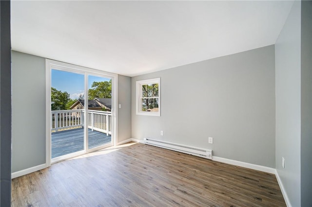 empty room with wood-type flooring and a baseboard heating unit